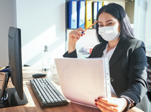 Woman working at desk wearing a mask
